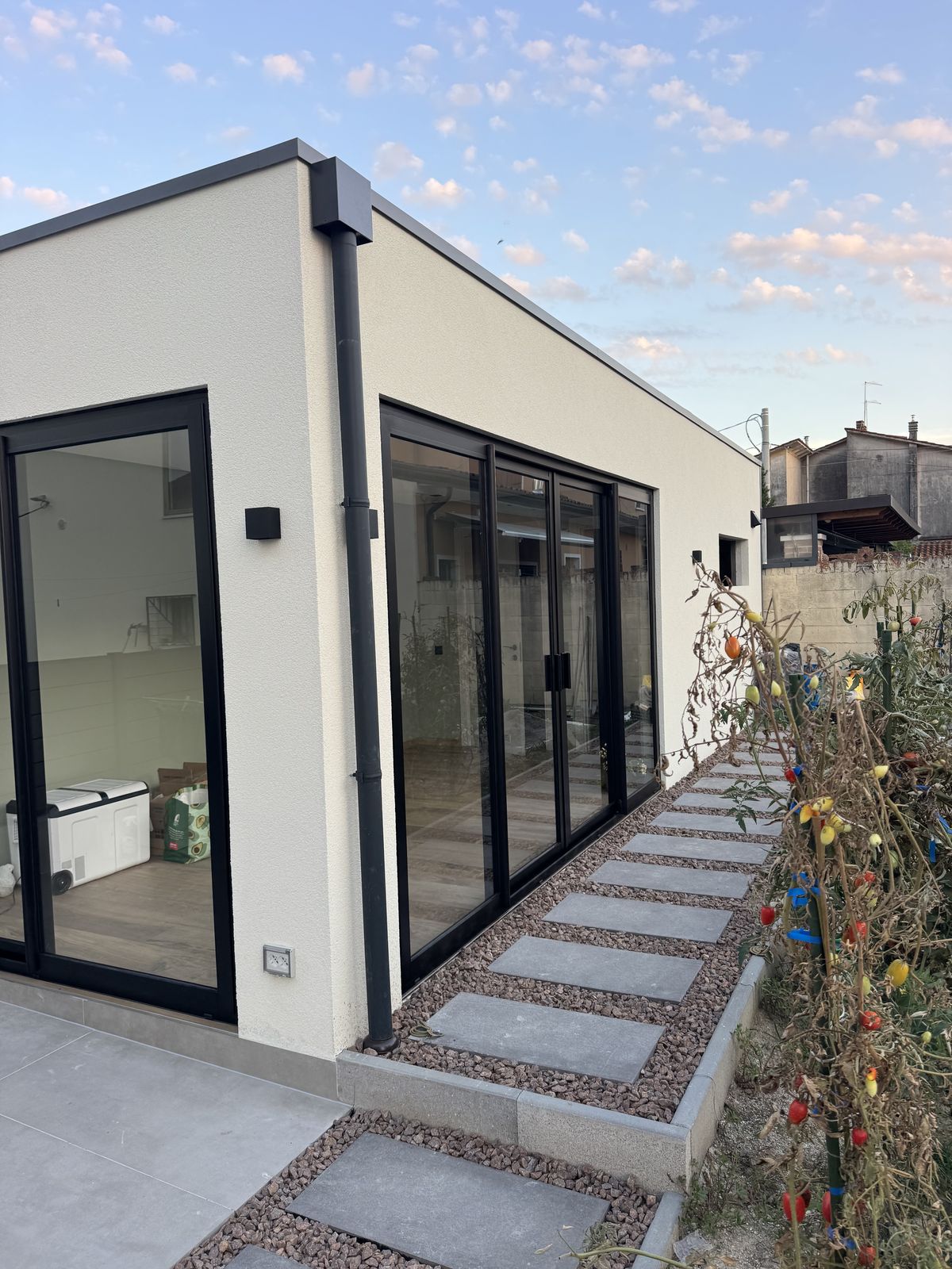 Anbau mit Glas-Schiebetüren und gepflastertem Gartenweg