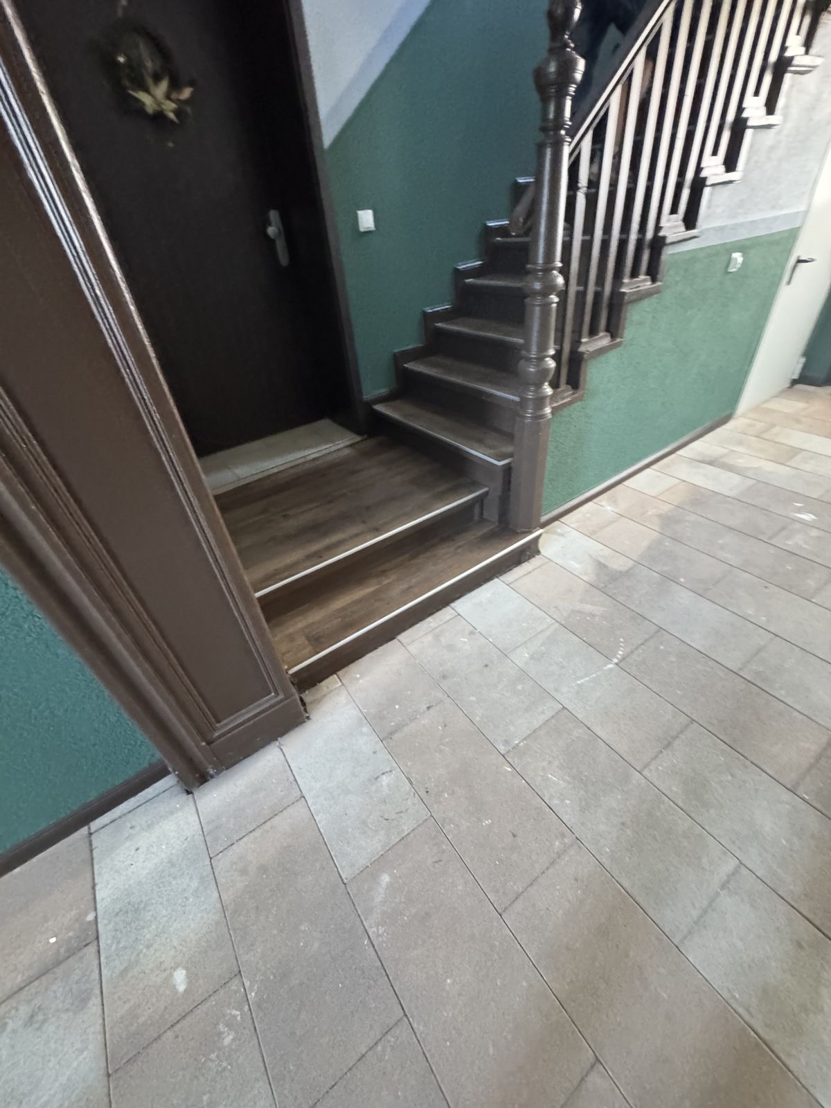 Sanierte Treppe mit Holzoptik-Belag und Fliesen im Treppenhaus